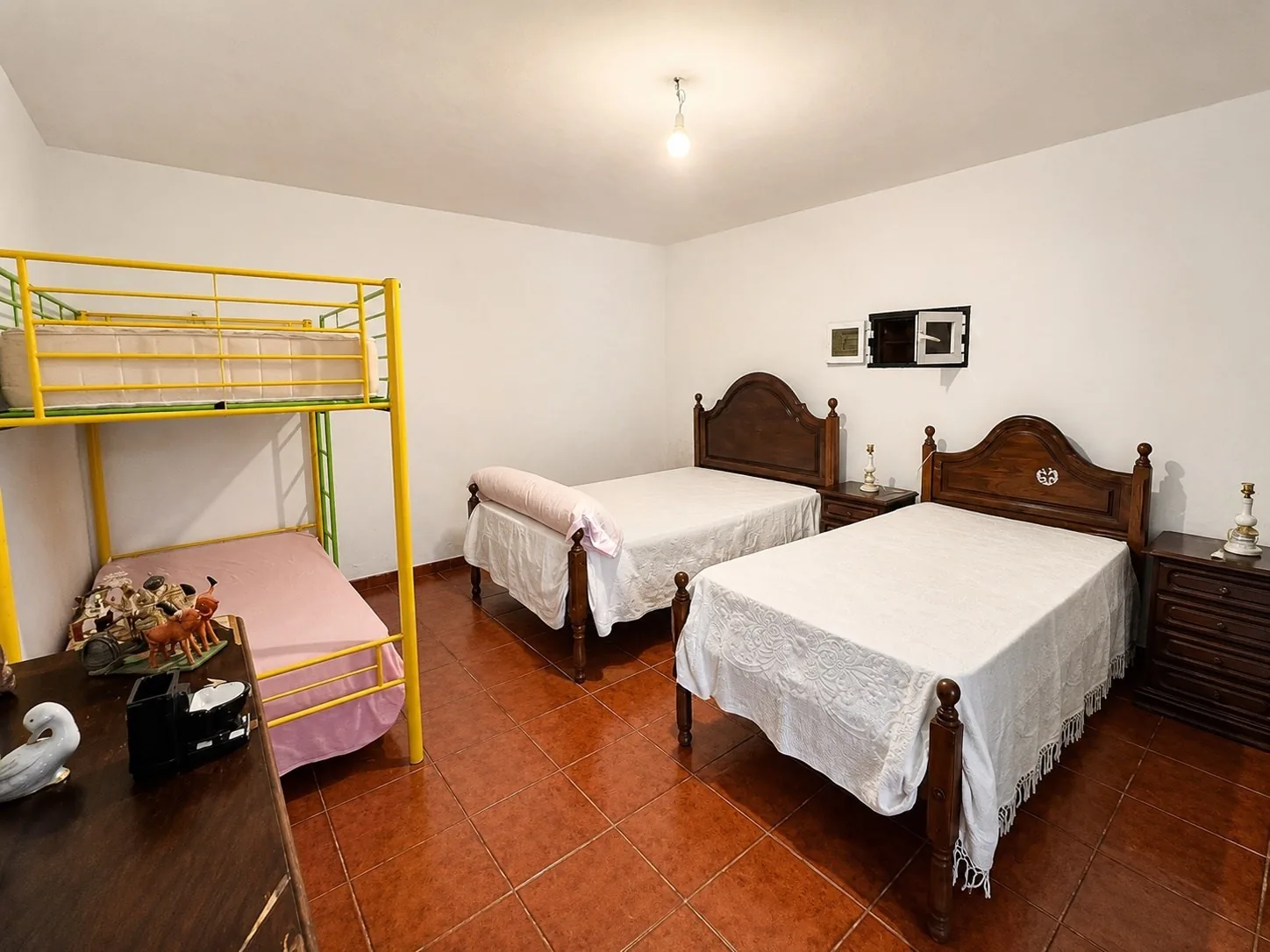 A children's room with a yellow bunk bed and two more single beds