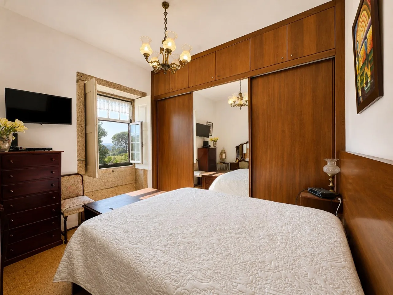 Renovated upstairs bedroom with a built-in wardrobe, cork floor, and a window looking out over the countryside
