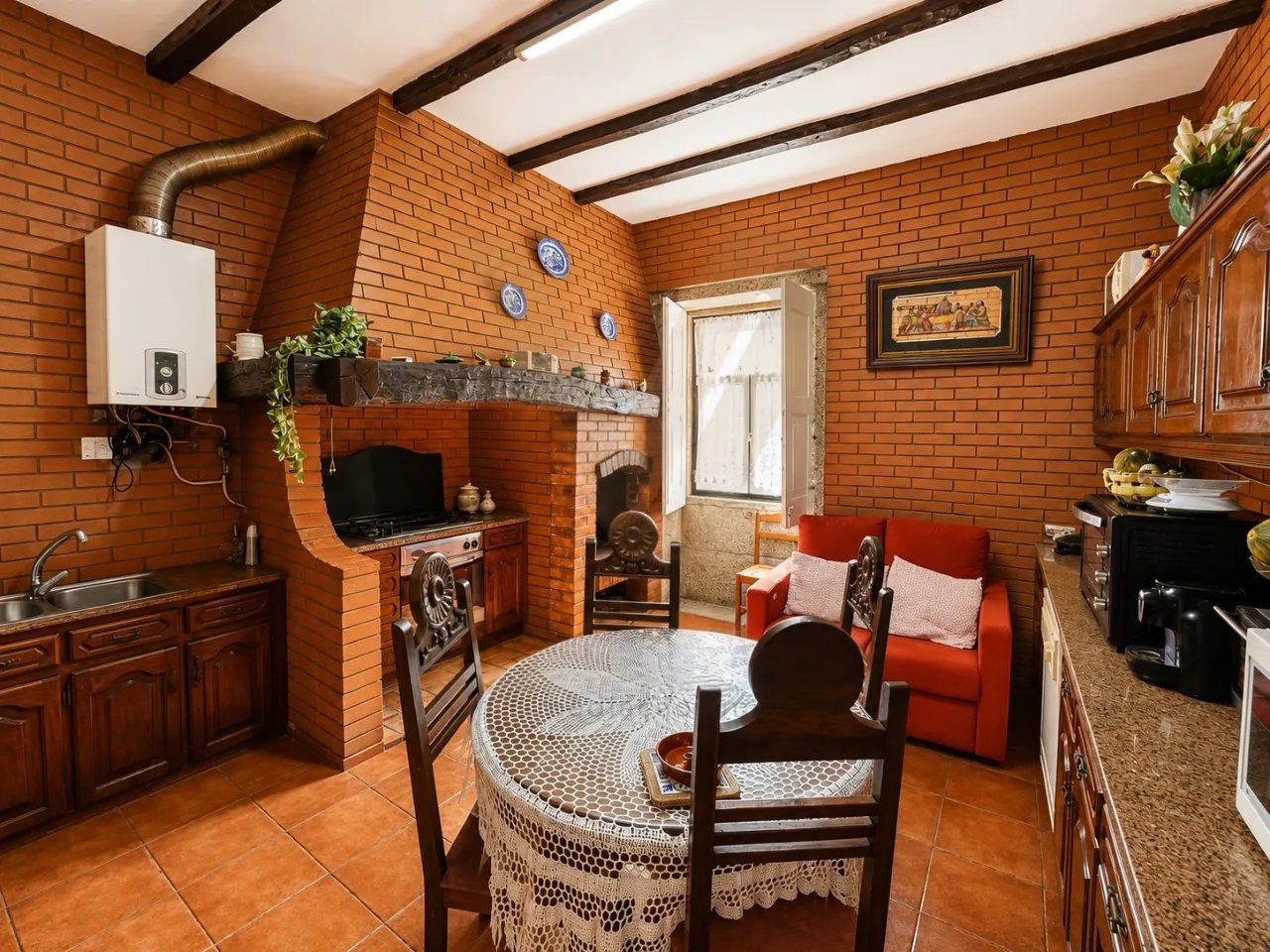 Rustic brick kitchen built around an old fireplace, with a gas cooktop set into the hearth and a small dining table