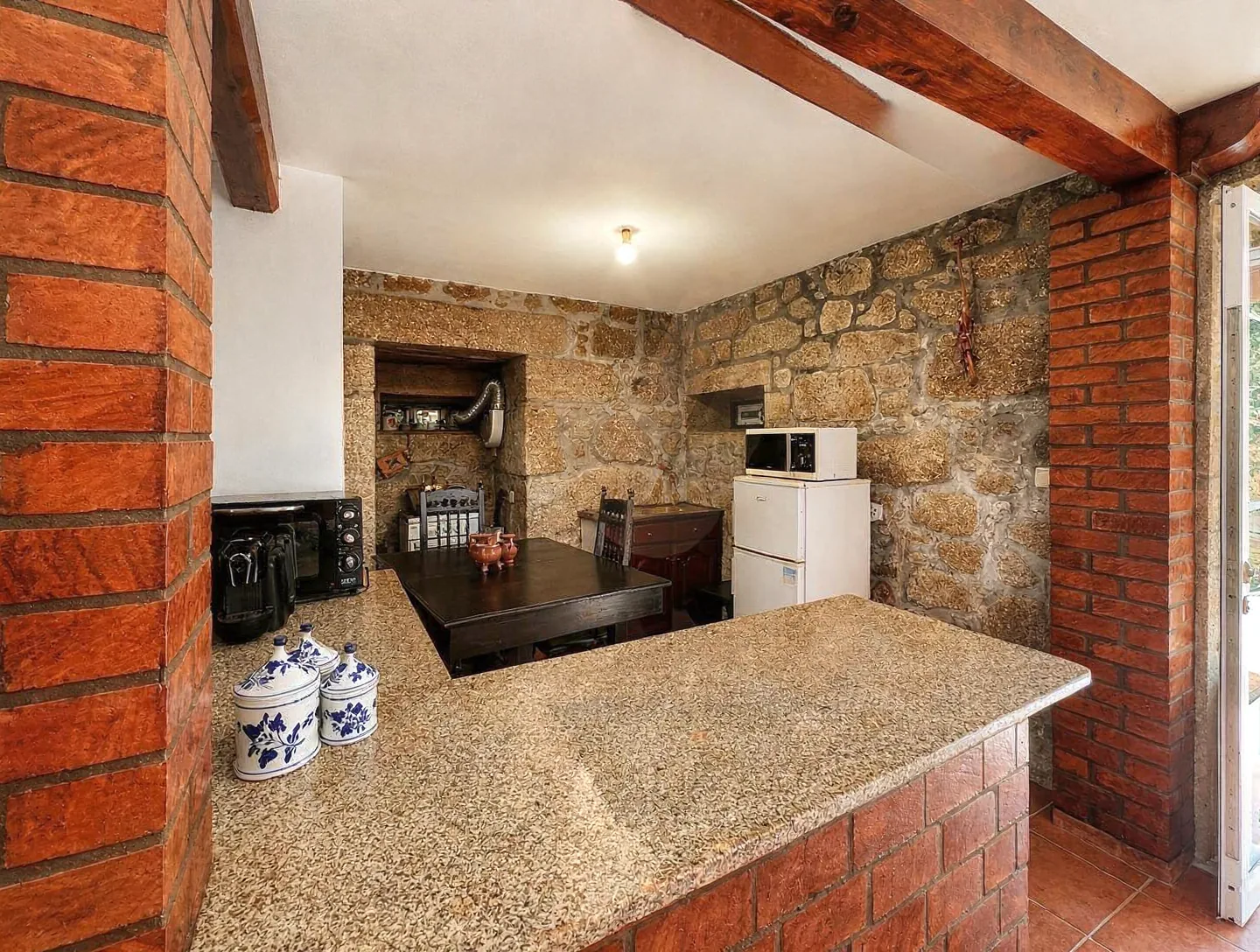 Second kitchen with exposed granite walls, a granite counter, and a small dining table