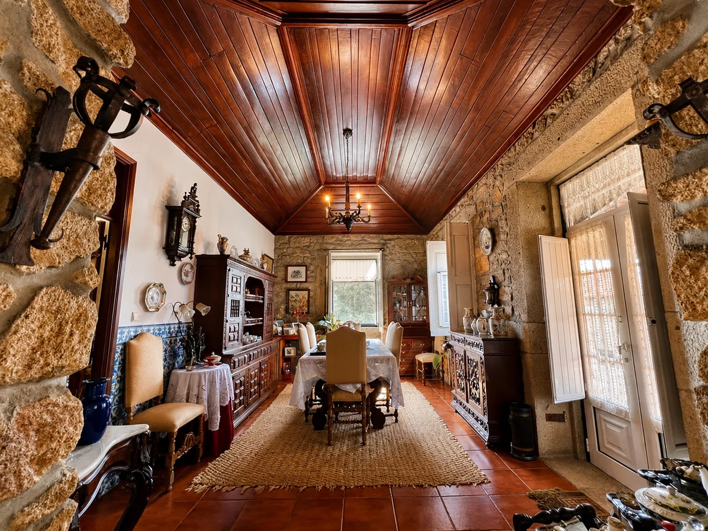 A more formal dining room with a vaulted wood-panelled ceiling, antique sideboards, and a woven rug
